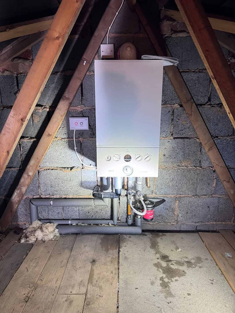 Boiler system installed in an attic space, showcasing plumbing and heating setup.