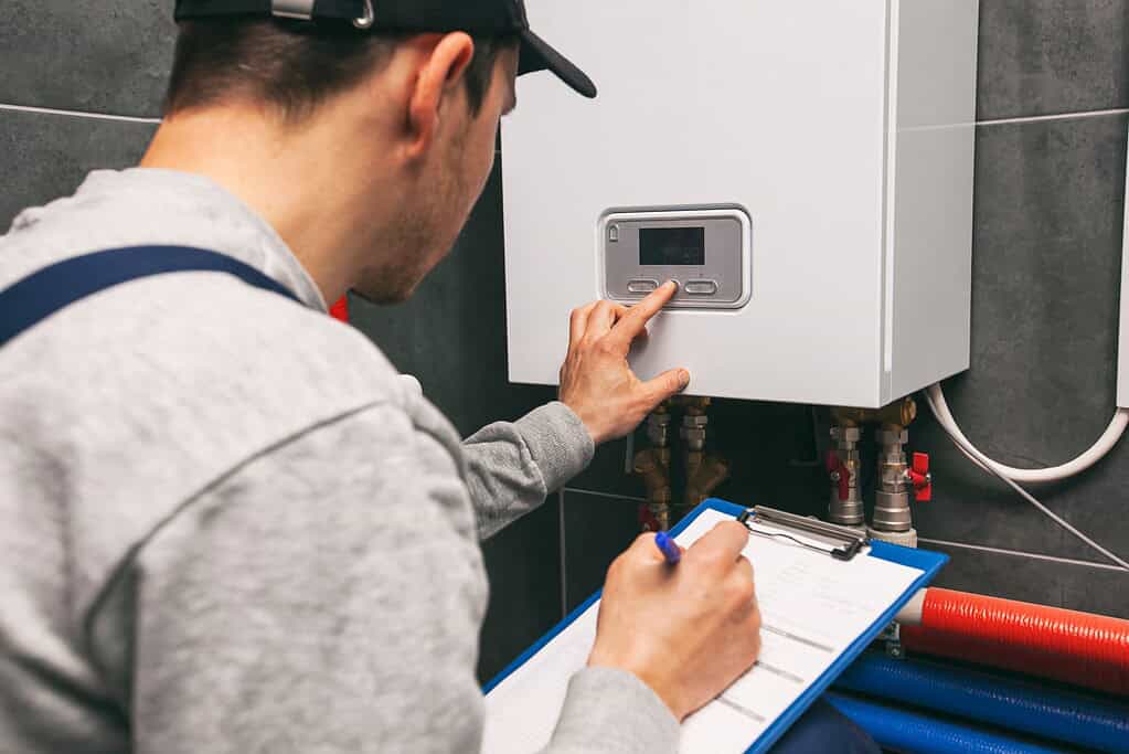 Plumber inspecting a boiler control panel in Derby.